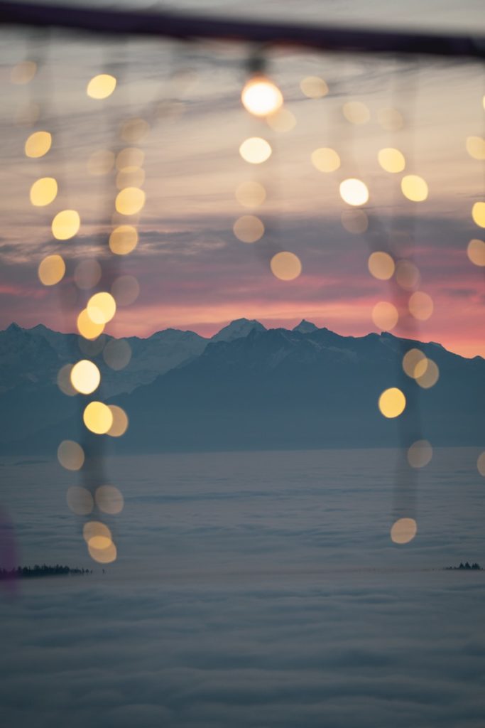 Bokeh lights over misty mountains at sunset