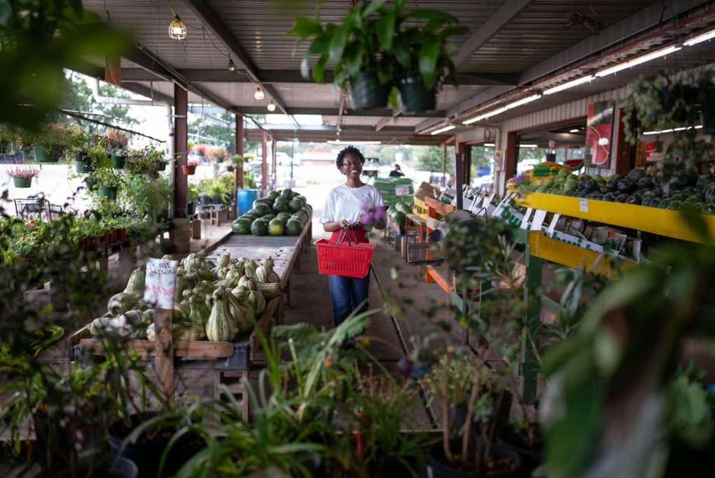 Woman shopping at a plant nursery with a basket